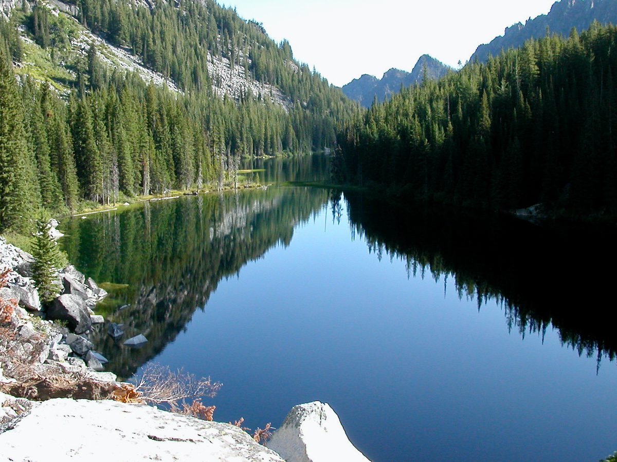 pristine lake surrounded by trees and hills