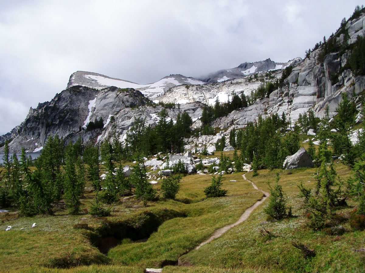 hiking paths through meadow going up to rocks above