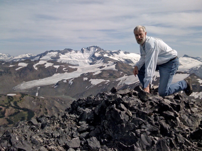 Larry kneeling with glacier beyond
