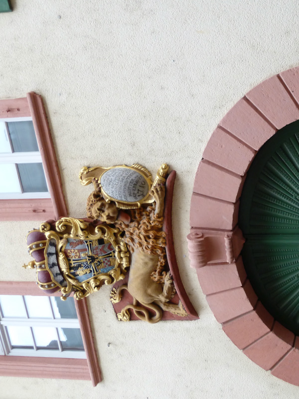 Big green arched door with inset door with royal crest overhead