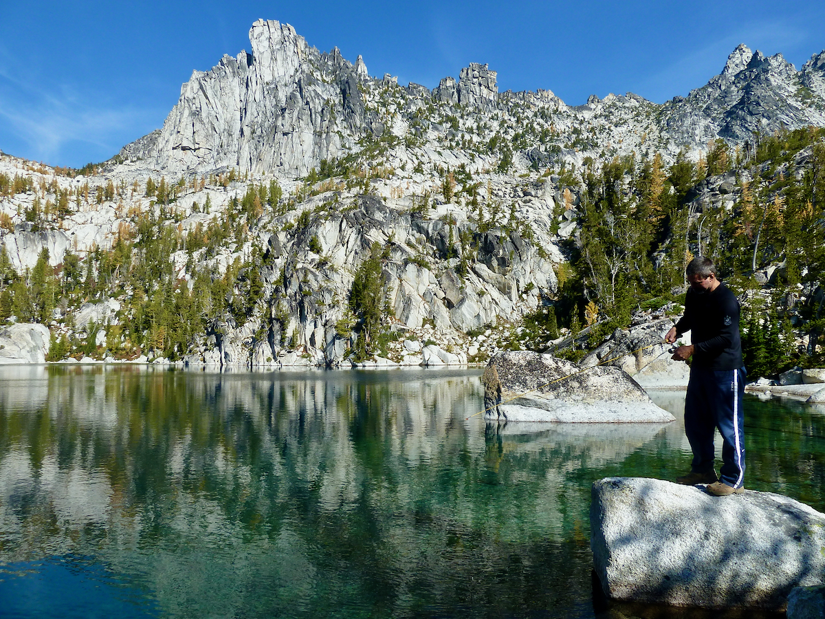 fisherman at lake with Prusik Peak wall beyond