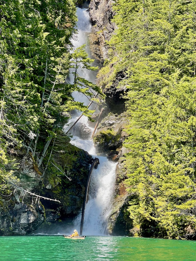 Tall waterfall with tiny kayak in front