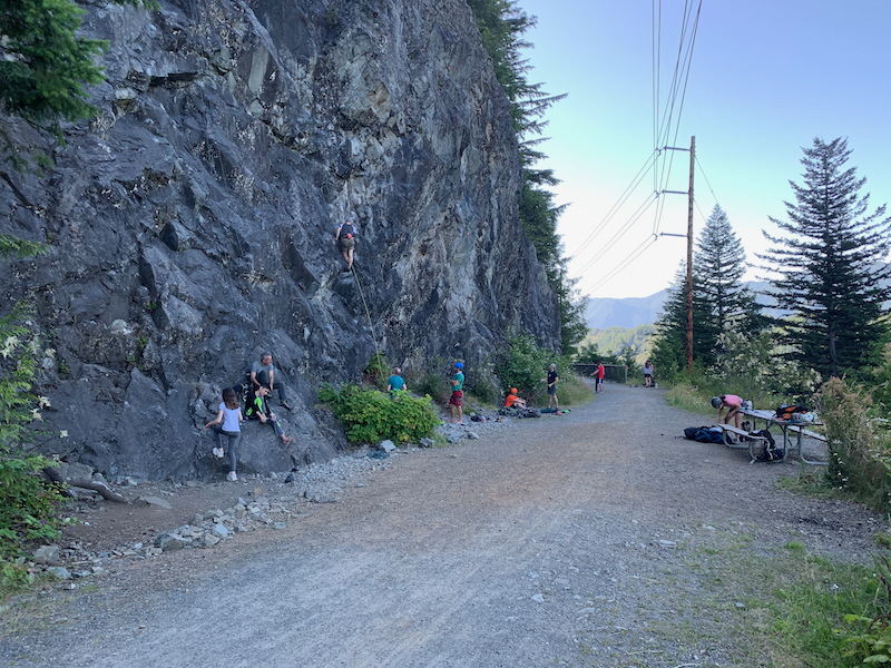people climbing on rocks adjacent to trail