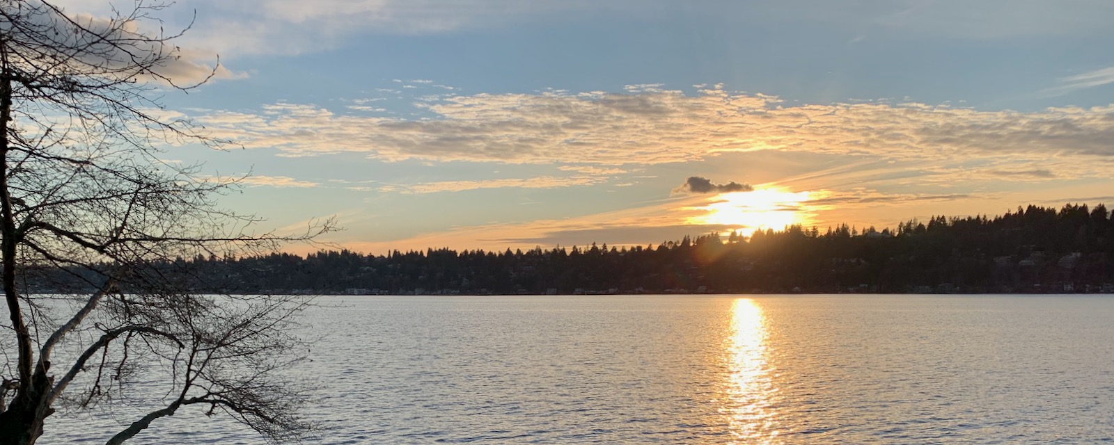 Sunset with light on the water, blue sky and clouds